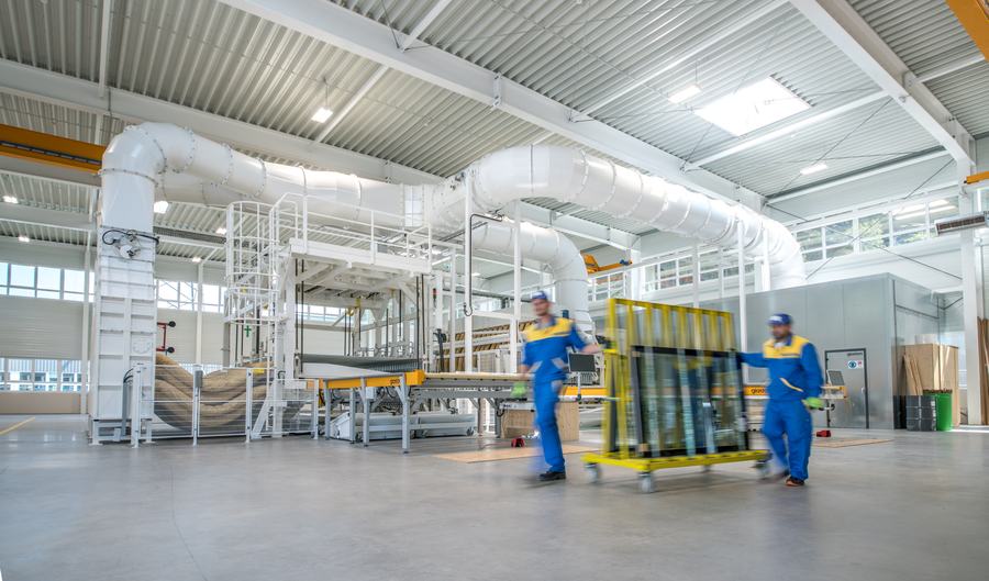 Zwei Mitarbeiter schieben einen Glastransportwagen durch die moderne Produktionshalle
